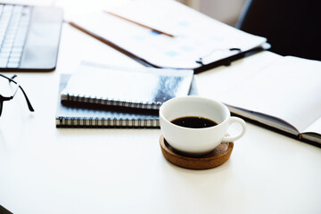 Focus on coffee mugs with books, documents with tablet computers on the desk