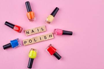 Obraz premium Many colorful nail polish bottles on pink background and copy space. Female beauty accessory.