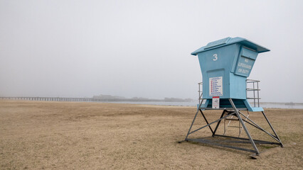 Lifeguard hut on beach in Santa Barbara with fog-shrouded pier in background