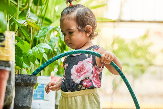 little latin girl taking care of the flora. girl watering the plants in her garden. Girl playing with water.