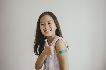 Mixed Asian preteen girl showing her arm with bandage after got vaccinated or inoculation, child immunization, covid omicron vaccine concept - obrazy, fototapety, plakaty