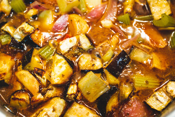 healthy plant-based food, vegan turkish güveç hot pot with eggplant celeri and potaotes in spicy broth with mixed herbs cooking on the stove
