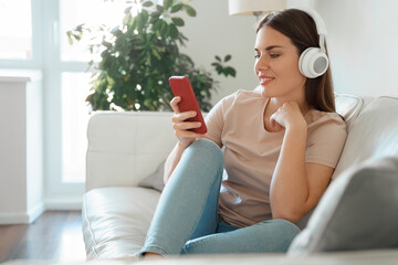 Young teenage woman in headphones watching online webinar on smartphone