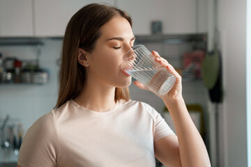 Thirsty young woman drinking fresh water from glass headshot portrait - obrazy, fototapety, plakaty
