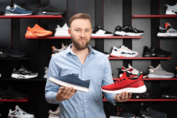 Young man choosing sneakers at sportswear shop, comfortable shoes in the sports shop, shopper...