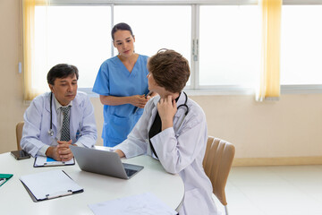 Multiracial medical team having a meeting with doctors in white lab coats and surgical scrubs seated at a table discussing a patients records, Medical team checking Xray results.