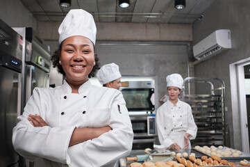 Young African American female chef in white cooking uniform looks at camera, arms crossed and...