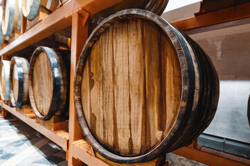 Huge wooden barrels of alcohol drinks on racks in cellar