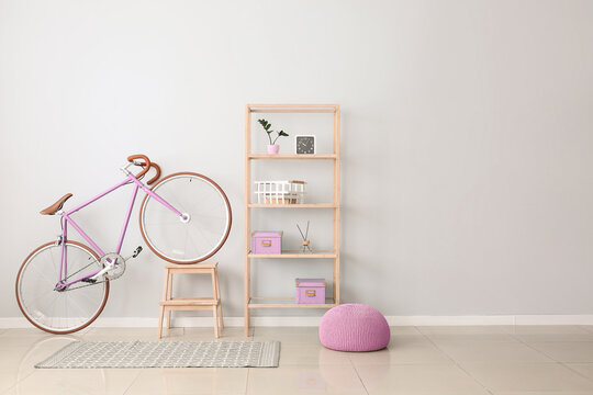 Bicycle, shelving unit and pouf near light wall
