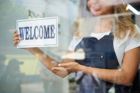 Cropped Image Of Smiling Hairdresser Hanging Welcome Sign On Wall To Attract More Customers