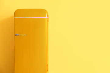 Stylish retro fridge on yellow background with space for text