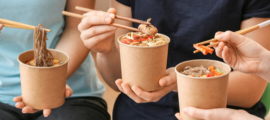 Women eating tasty Chinese noodles outdoors, closeup