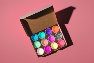 jars with acrylic paints in an open box on a colored background