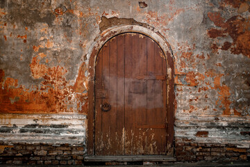 an old semicircular wooden door on the brick old facade of the house