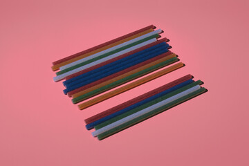 colored shiny hot gun glue sticks on pink background