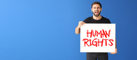 Angry  young man holding placard with text HUMAN RIGHTS on blue background