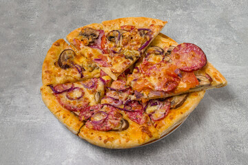 round pizza with sausage and mushrooms cut into pieces in a plate on the table