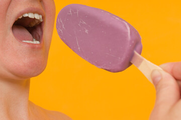 the woman opened her mouth wide and wants to bite off the ice cream. colored background