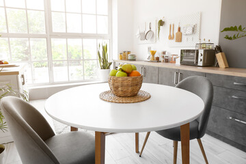 Wicker basket with fruits on dining table in kitchen