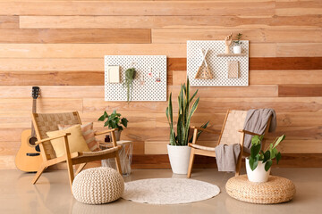 Interior of stylish living room with armchairs and pegboards near wooden wall