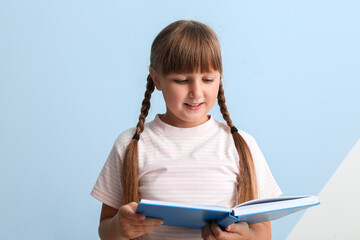 Little girl reading book on blue background
