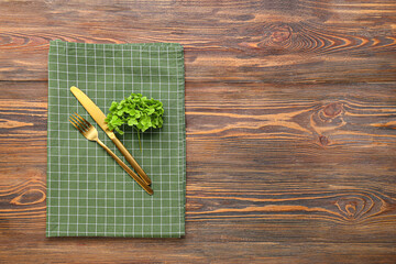 New checkered napkin for picnic, cutlery and plant on wooden background