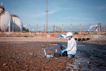 Scientist wearing protective uniform and glove under working water analysis and water quality by get waste water to check case in laboratory is environment pollution problem concept