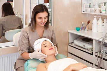 Obraz na płótnie Canvas Pretty young woman having facial massage in beauty salon