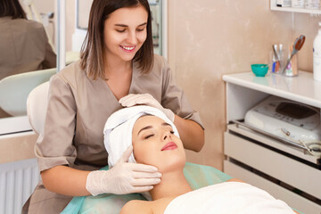 Obraz na płótnie Canvas Pretty young woman having facial massage in beauty salon