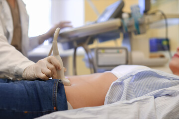 Fototapeta premium Young pregnant woman undergoing ultrasound scan in modern clinic