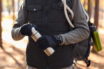 Male tourist with thermos in forest