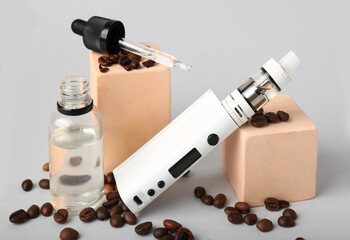 Modern vape mod, oil and coffee beans on grey background, closeup