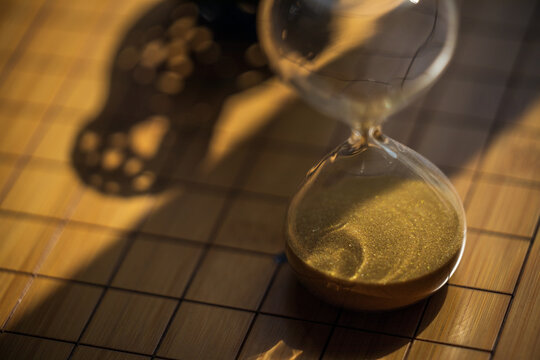 Hour glass with gold sand in dramatic lighting