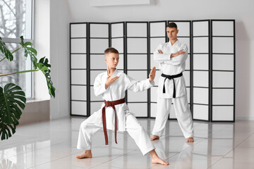 Boy practicing karate under watchful eye of instructor in dojo