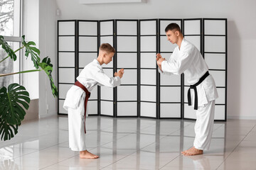 Boy and sensei performing ritual bow before practicing karate in dojo