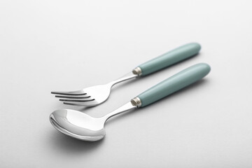 Stainless steel fork and spoon with green handle on light background