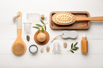 Set of different bath supplies with vacuum jars for anti-cellulite massage on white wooden background