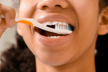 African-American teenage girl brushing teeth in bathroom, closeup