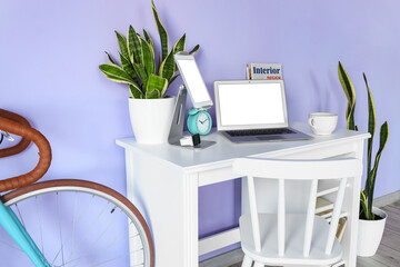 Tablet computer, laptop and smartwatch on table near color wall