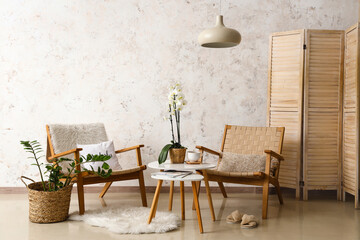 Interior of room with armchairs and table near light wall - obrazy, fototapety, plakaty