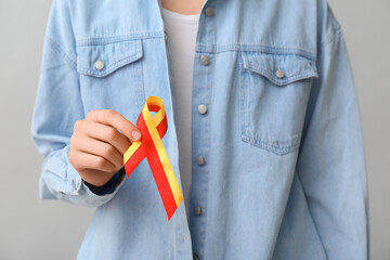 Woman with awareness ribbon on grey background, closeup. Hepatitis concept