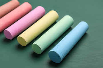 Colorful chalks on green blackboard, closeup