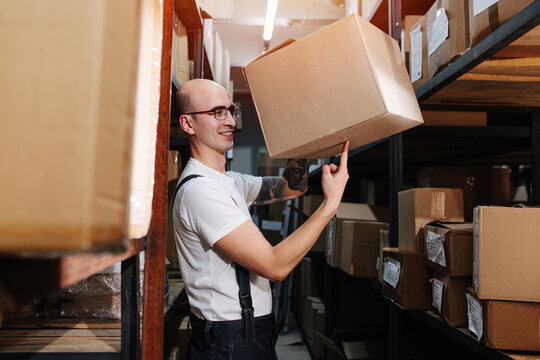 Bored Male Warehouse Worker Playing With A Box, Holding It On One Finger