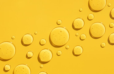 round drops of transparent gel serum on a yellow background - obrazy, fototapety, plakaty