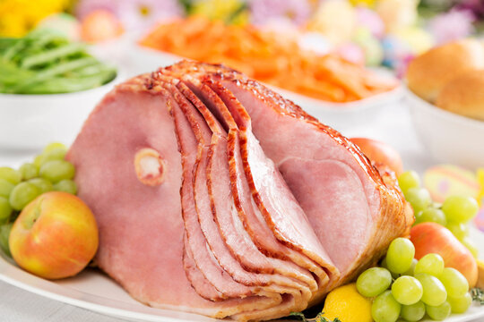A spiral cut ham with carrots, green beans, bread and spring flowers for Easter dinne