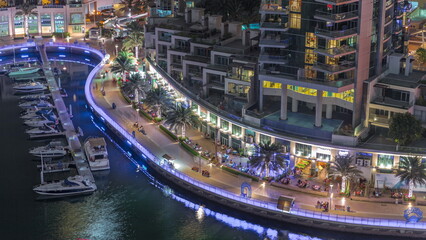 Naklejka premium Waterfront promenade with palms in Dubai Marina aerial night timelapse.