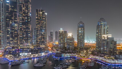 Fototapeta na wymiar Dubai Marina luxury tourist district with skyscrapers and towers around canal aerial night timelapse
