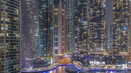 Waterfront promenade with palms in Dubai Marina aerial night timelapse.