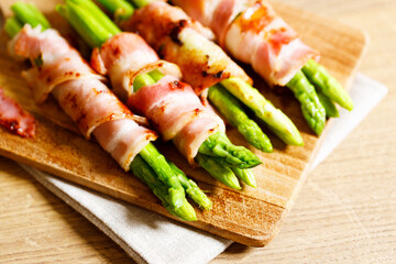 Bacon wrapped asparagus on wooden plate.