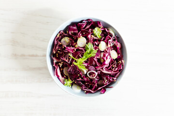 Obraz na płótnie Canvas red cabbage salad, coleslaw, in a bowl on white wooden table.